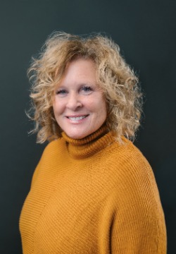 Woman wearing orange sweater smiling.